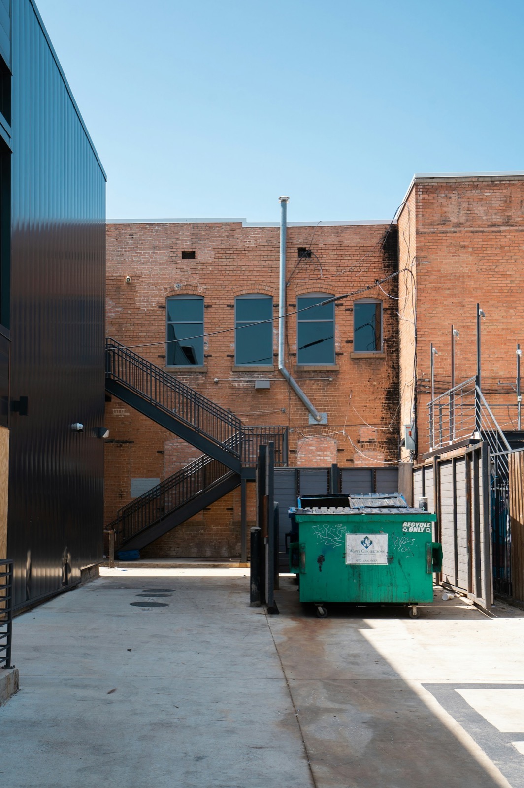 Green dumpster beside a brown building — typical roll-off dumpster rental